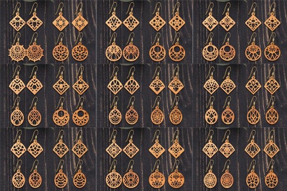 Laser cut wood earrings displayed in multiple rows featuring various intricate geometric and floral designs