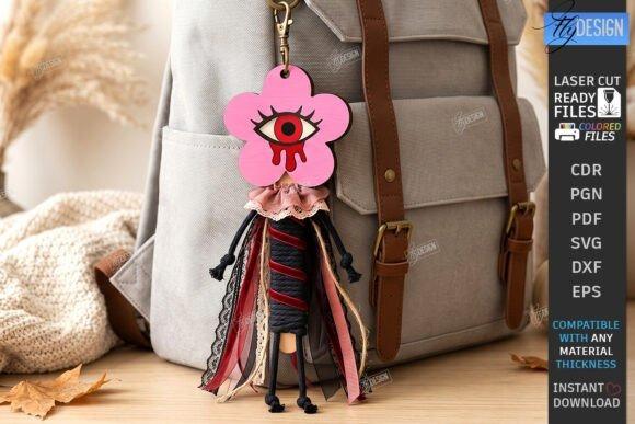 Laser Cut Halloween Keychain Pink flower-shaped wooden laser cut Halloween keychain with large central eye hanging on beige backpack