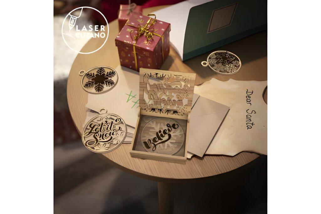 54 Christmas Laser Cut Files for Festive Laser Projects 4 Christmas Laser Cut Files showing multilayer ornaments and decorative boxes on a wooden table with a gift and letter